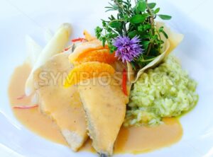 Fried fish with green risotto decorated with herbs and flowers