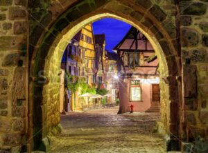 View of Riquewihr, Alsace, France, through city wall gate at night