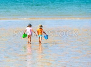 Two children playing on a sand beach at sea - GlobePhotos - royalty free stock images