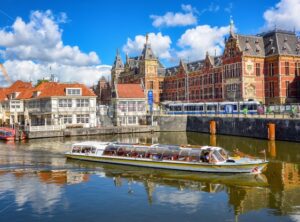 Tourist boat in front of the central train station in Amsterdam city, Netherlands