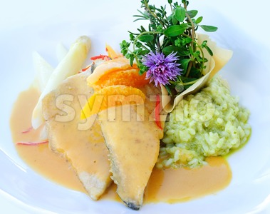 Fried fish with green risotto decorated with herbs and flowers Stock Photo